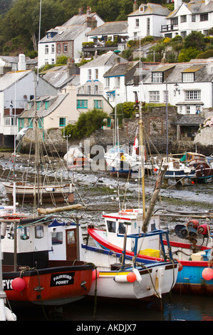Whitewashed houses overlooking Polperro Harbour at low tide exposing the moored boats hulls. Cornwall, UK Stock Photo