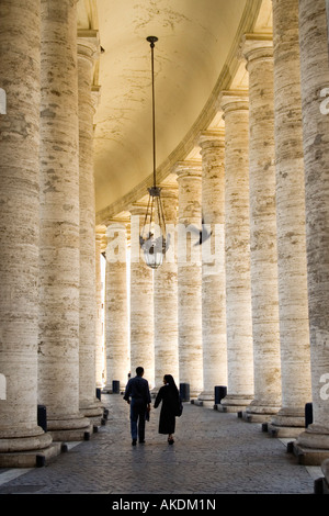 A priest and a nun walking under the colonnade of the Vatican Stock Photo