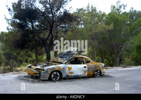 Burnt car ( Toyota Celica ) on a street along a forest Stock Photo