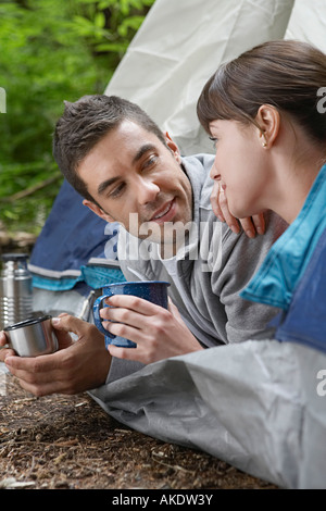 Couple with drinks, lying in tent entrance Stock Photo
