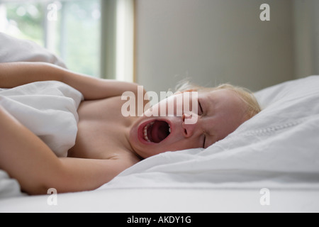 Young girl (1-2) lying in bed, yawning Stock Photo