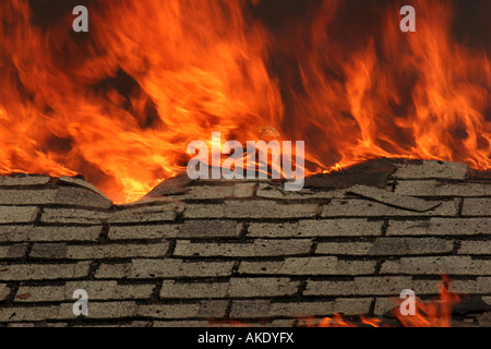 A roof on fire and the shingles are being burnt off as the attic rafters calapses Stock Photo