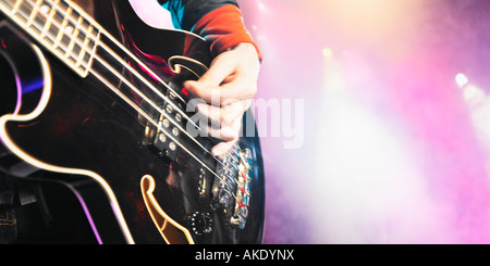 Close-up of man playing bass guitar at concert, mid section Stock Photo