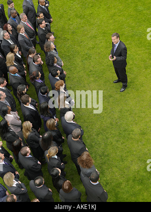 Business man facing large group of business people in formation, elevated view Stock Photo