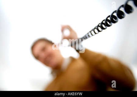 Man making telephone call with focus on the telephone cable Stock Photo