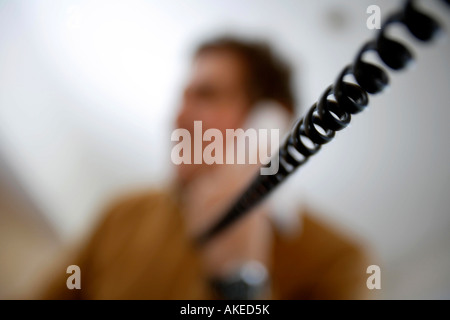 Man making telephone call with focus on the telephone cable Stock Photo