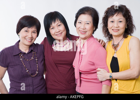 Portrait of three senior women and a mature woman standing together and smiling Stock Photo