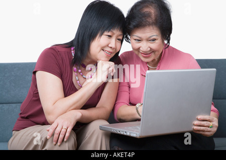 Close-up of a mature woman and a senior woman using a laptop and smiling Stock Photo