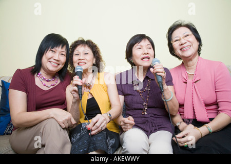 Three senior women and a mature woman singing in front of microphones Stock Photo