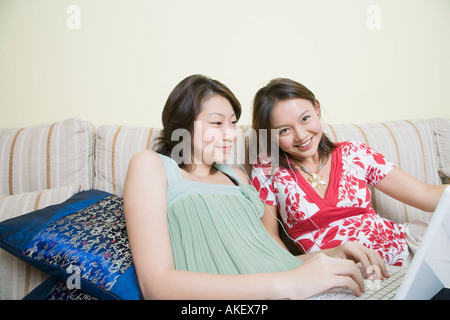 Portrait of a young woman smiling with another young woman using a laptop Stock Photo