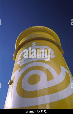 a yellow spanish post box in mijas lit up against a strong blue sky Stock Photo