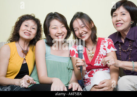 Two young women singing with their grandmothers into microphones Stock Photo