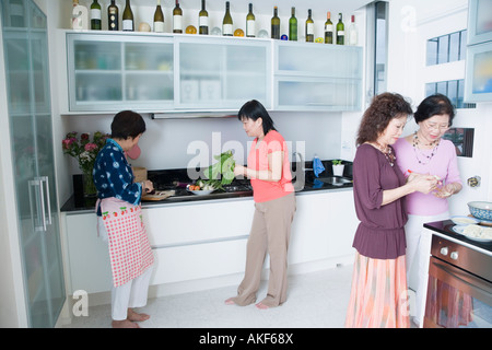 Three senior women and a mature woman preparing food in a domestic kitchen Stock Photo