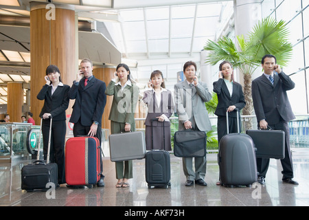 Business executives talking on mobile phones at an airport lounge Stock Photo