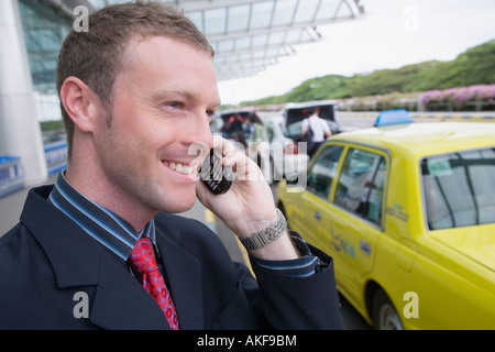 Close-up of a businessman talking on a mobile phone outside an airport Stock Photo