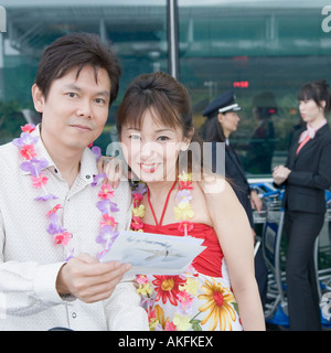 Mature couple looking at an airplane ticket with a pilot and a cabin crew standing in the background Stock Photo