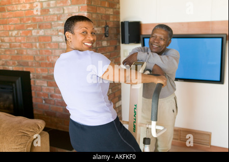 Seniors African Americans Exercising on stepper machine and plasma TV Stock Photo