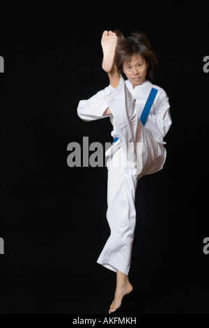 Portrait of a young woman performing front kick Stock Photo