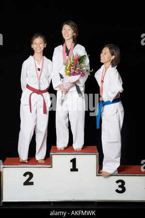 Three young women standing on a winners podium with their medals Stock Photo