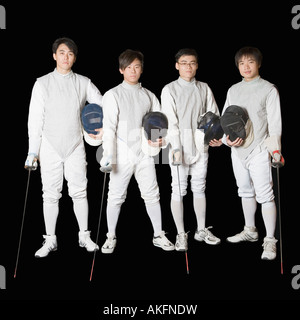 Portrait of four male fencers holding fencing foils and fencing masks Stock Photo