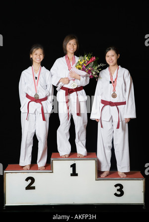 Three young women standing on a winners podium with their medals and smiling Stock Photo