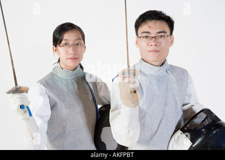 Portrait of a male with a female fencer holding fencing masks and fencing foils Stock Photo