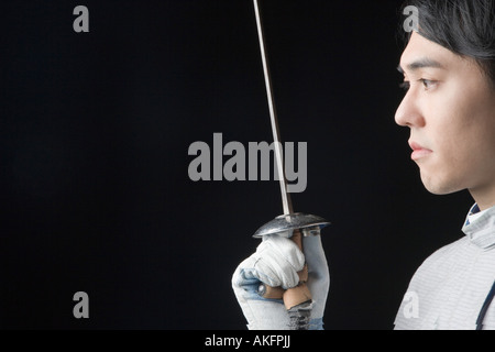 Side profile of a male fencer holding a fencing foil Stock Photo