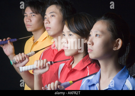 Close-up of two young women and two young men standing side by side with badminton rackets Stock Photo