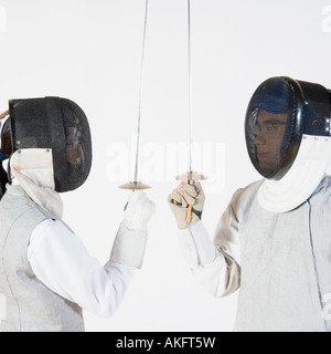 Close-up of a man and a woman wearing fencing masks and holding fencing foils Stock Photo