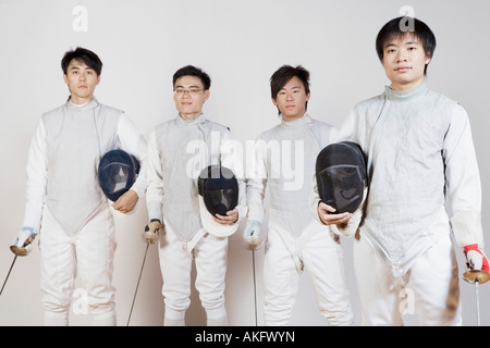 Portrait of four male fencers holding fencing foils and fencing masks Stock Photo