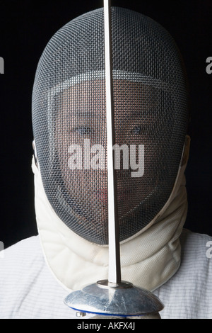 Portrait of a female fencer holding a fencing foil in front of her Stock Photo