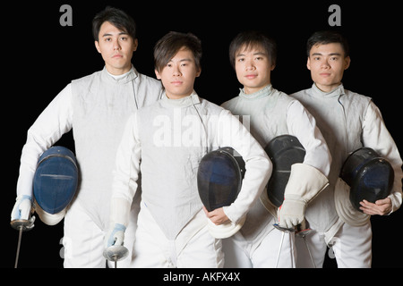 Portrait of four male fencers holding fencing foils and fencing masks Stock Photo