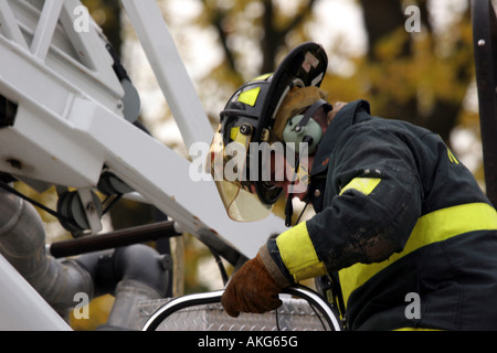 A firefighter climbing down from the control platform of the ladder truck Stock Photo