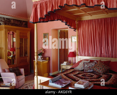 Four poster bed with pink canopy and drapes in pink townhouse bedroom Stock Photo