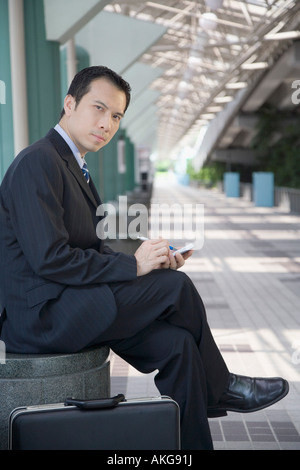 Portrait of a businessman sitting and using a palmtop Stock Photo