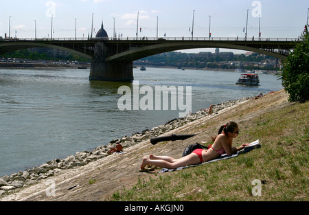 Girl sunbathing along the riverbank Budapest Hungary Stock Photo