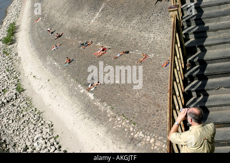 People sunbathing along the Danube riverbank Budapest Hungary Stock Photo