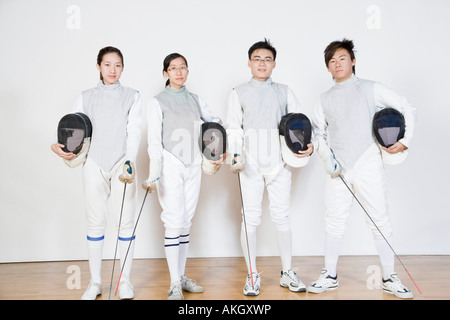 Portrait of two male and two female fencers holding fencing masks with fencing foils Stock Photo