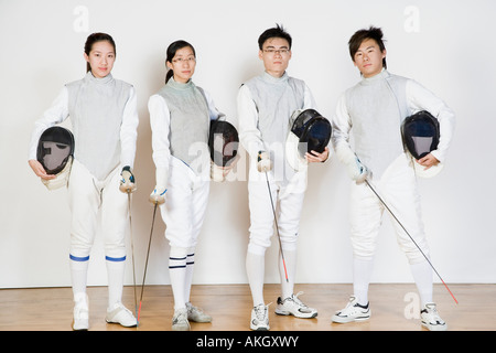 Portrait of two male and two female fencers holding fencing masks with fencing foils Stock Photo