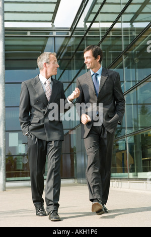 Two businessmen walking along office building Stock Photo
