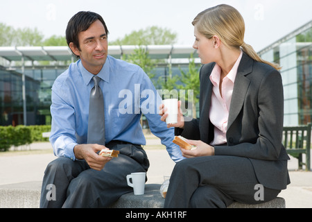 Businesswoman and businessman eating sandwiches outdoors Stock Photo