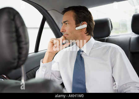 Businessman with bluetooth headset sitting in car Stock Photo