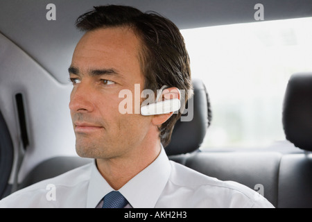 Businessman with bluetooth headset sitting in car Stock Photo