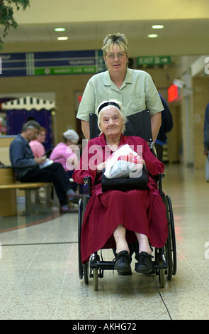 Elderly disabled woman is taken shopping by her carer UK Stock Photo