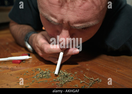 Man Sucking Marijuana into a Normal Cigarette with the Tobacco and Filter Removed to make an Italian Style Joint Stock Photo