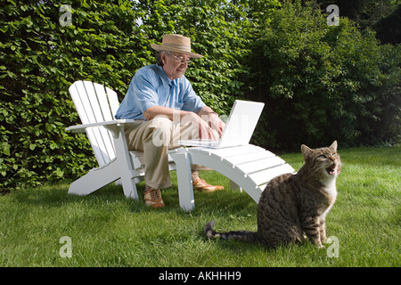 Man in garden with laptop and cat Stock Photo