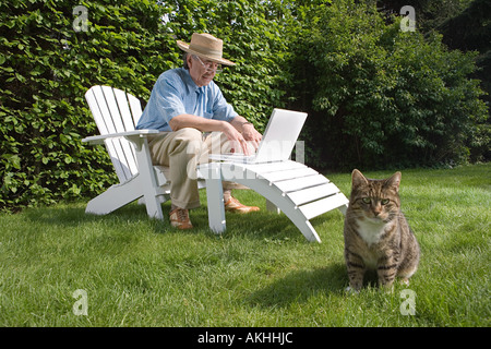 Man in garden with laptop and cat Stock Photo