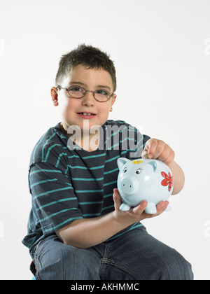 Boy putting coin in piggy bank Stock Photo