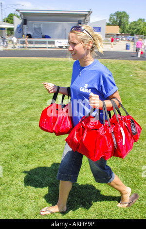 Teenager girl carries free picnic lunch bags to Seniors at their annual picnic in Marysville Michigan MI Stock Photo