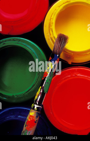 Jars of colorful paint with used paint brush Stock Photo